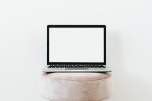 - Above The Bar - Above The Bar Blank laptop sits on round white cushion against a white background - - Above The Bar - - Above The Bar